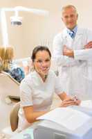 Dentist with assistant smiling at dental surgery