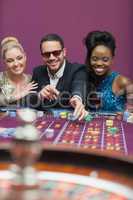 Man wearing sun glasses with women at roulette