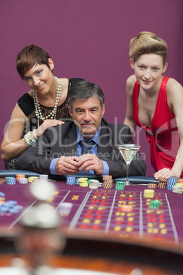 Women standing with man at roulette table