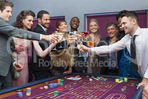 People standing clinking glasses at roulette table
