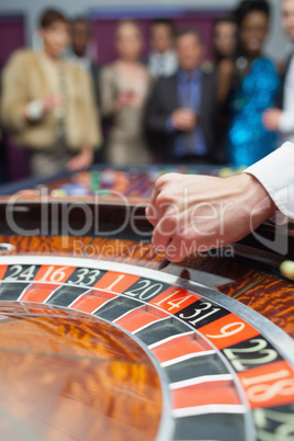 Dealer dropping ball into roulette wheel