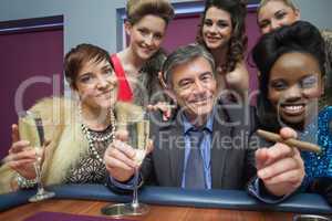 Happy man surrounded by women at roulette table