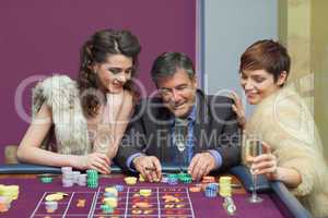 Man and two women talking at roulette table
