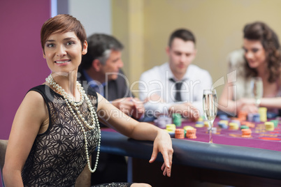 Smiling woman taking break from roulette with champagne