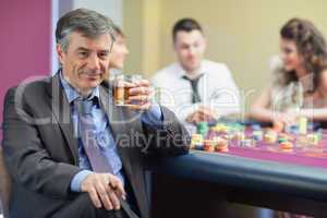Man drinking whiskey at roulette table