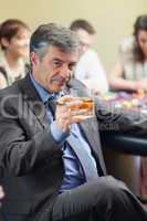 Man with cigar raising whiskey glass at roulette table