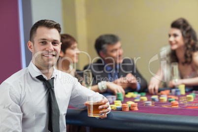 Young man with whiskey looking up from roulette table