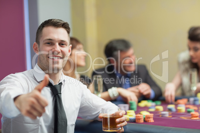 Man giving thumbs up and holding whiskey glass