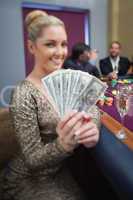 Blonde fanning dollars at roulette table