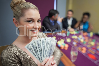 Blonde woman holding fan of dollars