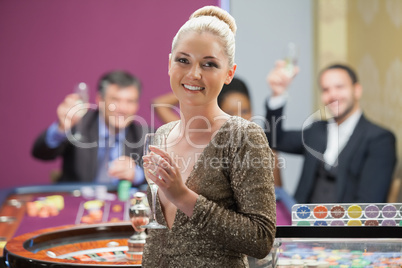 Woman holding champagne glass as people are cheering behind her