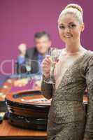 Woman smiling with champagne glass at roulette wheel
