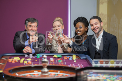 Four people toasting with champagne at roulette