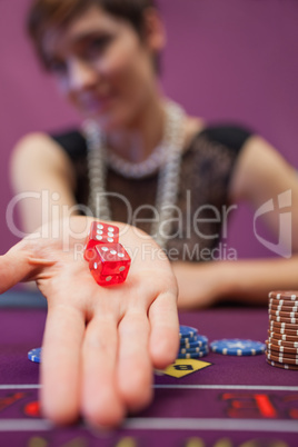 Woman sitting at table while holding dices