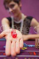 Woman sitting at table while holding dices