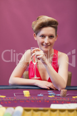 Woman sitting at table while holding a glass of champagne