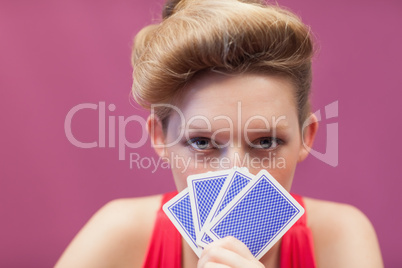 Woman in a casino holding cards up to face