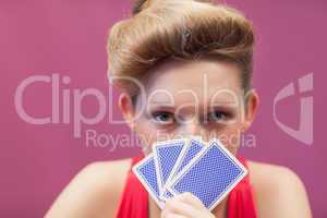 Woman in a casino holding cards up to face