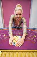 Smiling woman grabbing chips in a casino
