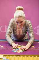 Woman in a casino grabbing chips