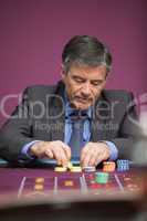 Man grabbing chips and playing roulette