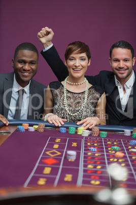 Three happy people at roulette table