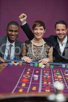 Three happy people at roulette table