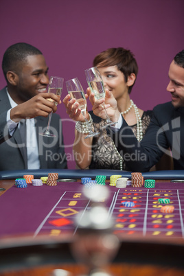 Three people celebrating in a casino with champagne