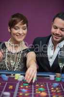 Woman placing roulette bet with man