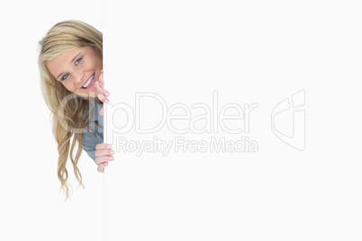 Blue-eyed woman hiding behind a poster