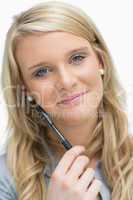 Woman smiling and holding pen to face