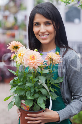 Employee smiling and holding a flower in garden center