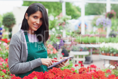 Smiling employee using tablet pc to check flowers