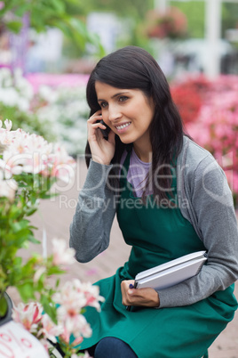 Employee doing stocktaking while calling in garden center