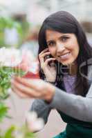 Smiling florist touching a flower and making a call