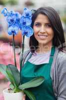 Brunette woman holding a blue flower working in garden center