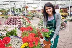 Cheerful woman planting a flower in a flower pot