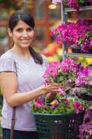 Black-haired woman holding pink flowers in garden center