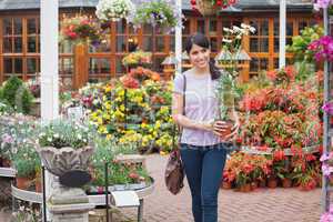 Woman carrying a daisy plant through garden center