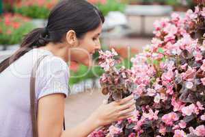 Black-haired woman smelling flower