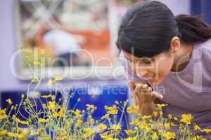 Woman smelling yellow flowers happily