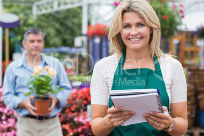 Smiling woman holding notepad with customer holding plant