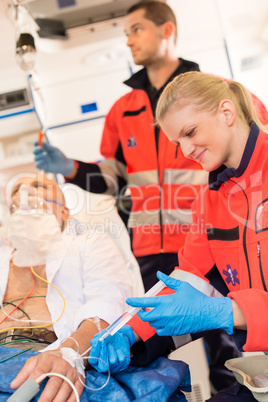 Paramedics injecting sick patient in ambulance aid