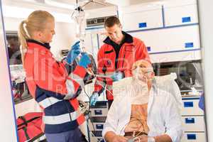 Paramedic putting oxygen mask on patient ambulance