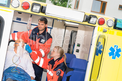 Paramedics checking IV drip patient in ambulance