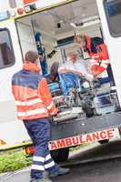 Paramedics putting patient in ambulance car aid