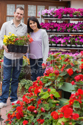 Happy couple carrying tray of plants