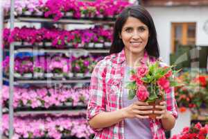 Woman standing in front of shelves and holding a flower