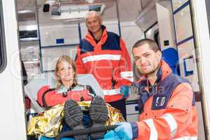 Paramedics helping woman on stretcher in ambulance
