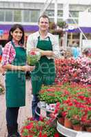Two garden center workers with one holding flower pot